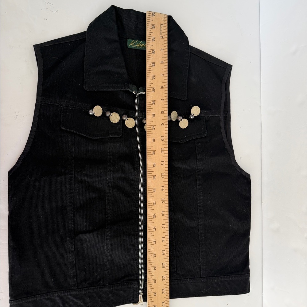 black denim vest featuring unique coin-style metal accents across the chest.